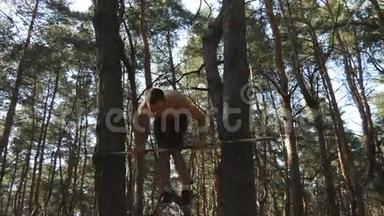 强壮的肌肉男在森林里的水平杆上做倒立。 肌肉男健身男在木头上做特技